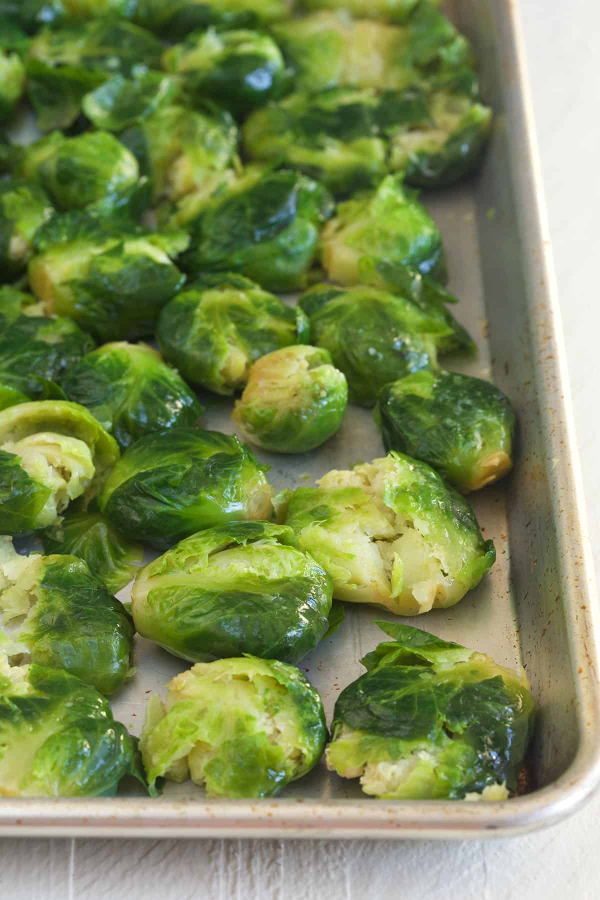 Smashed brussels sprouts are presented on a baking sheet.