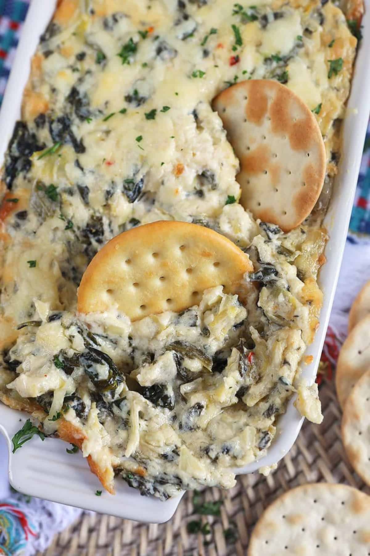 Two crackers dipped into spinach artichoke dip