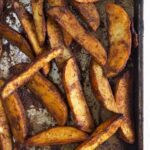 Cooked fries are spread out on a baking sheet.