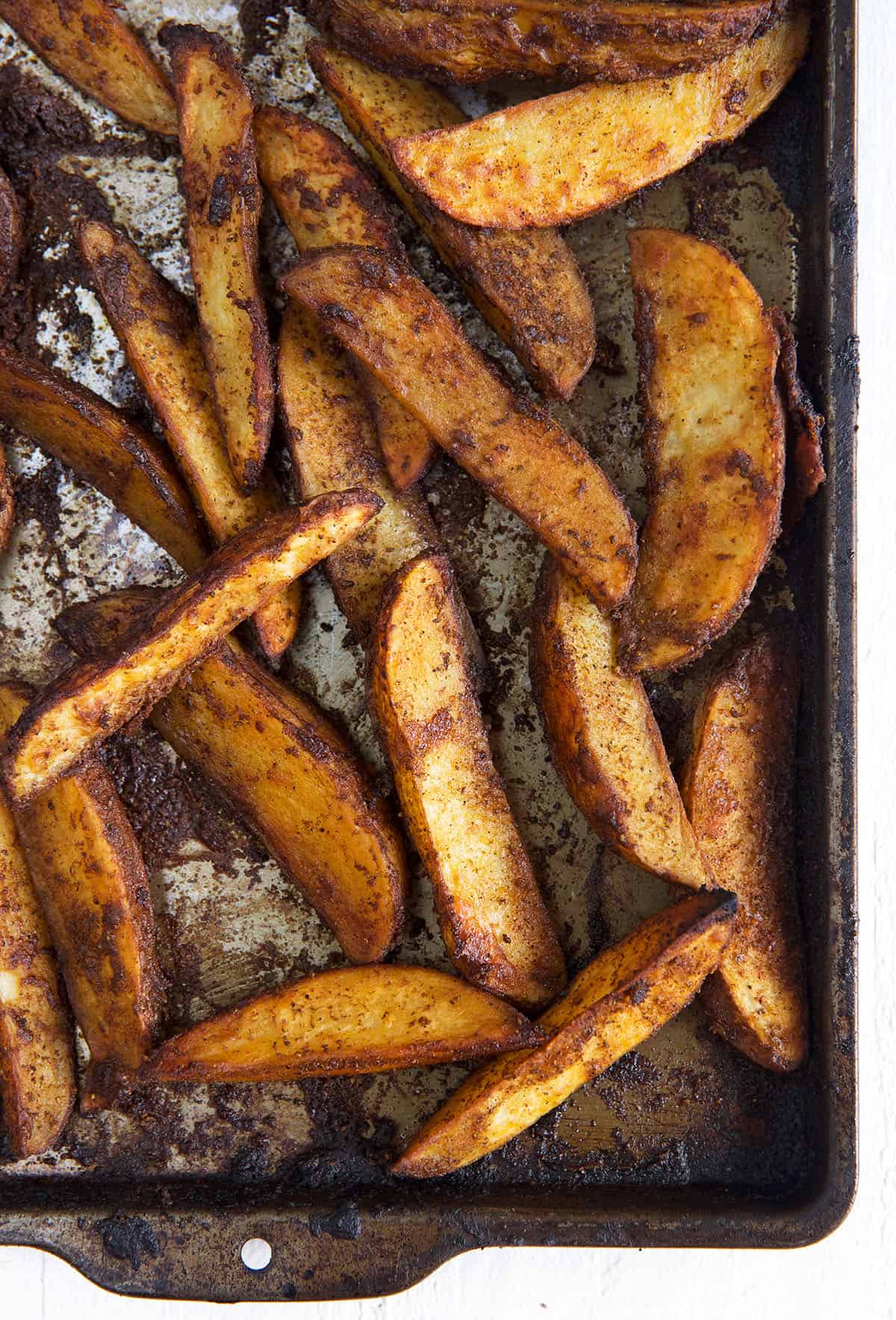Cooked fries are spread out on a baking sheet.