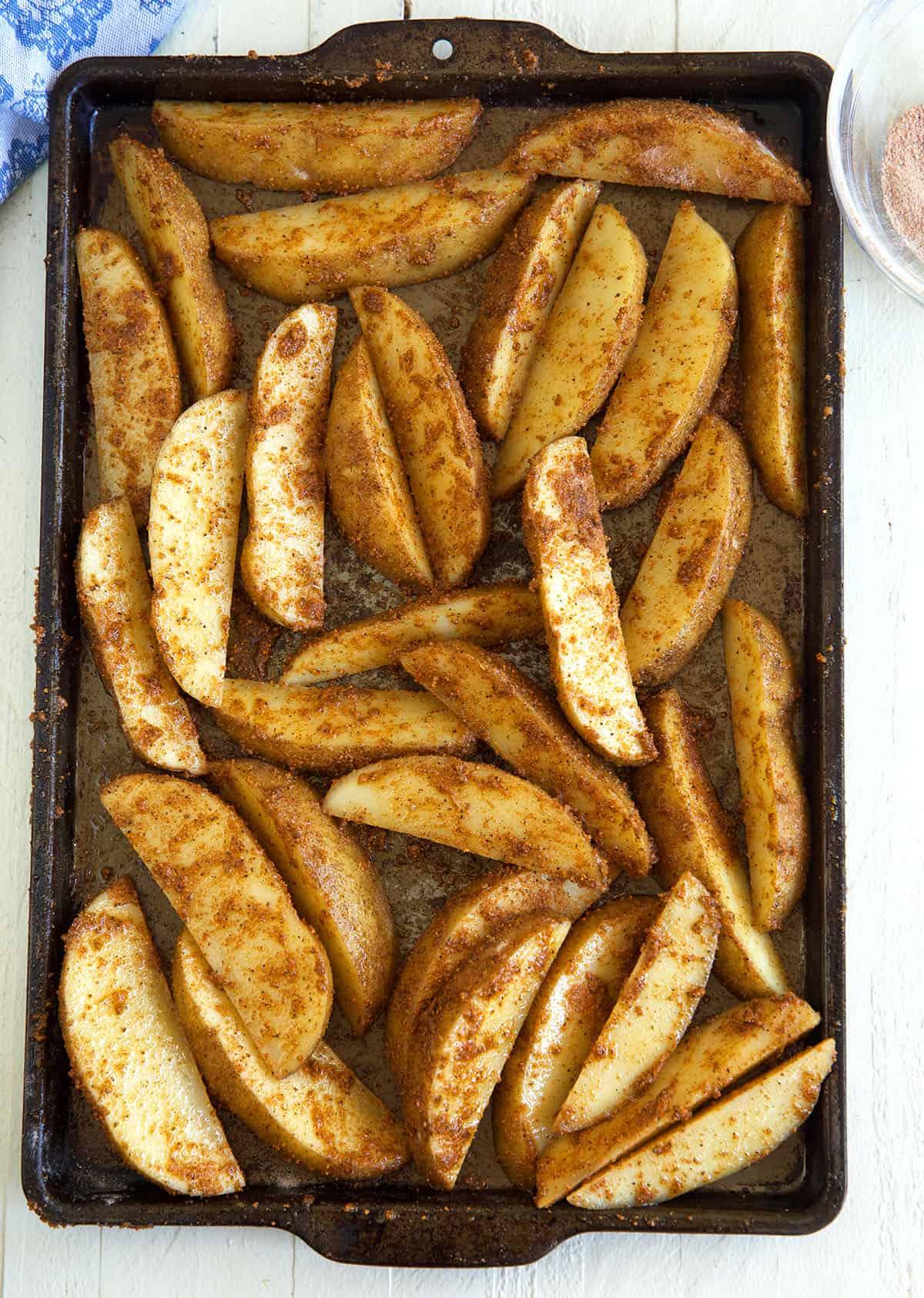 Seasoned, uncooked wedges are spread in a single layer on a baking sheet.