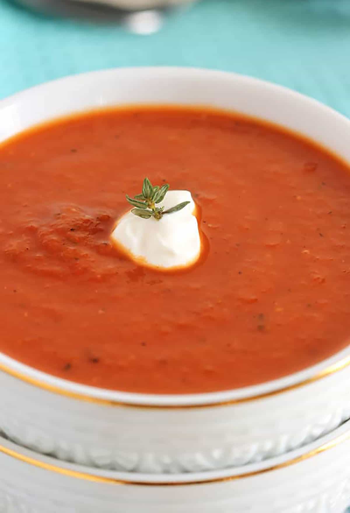 Tomato soup in a white bowl on a blue background.