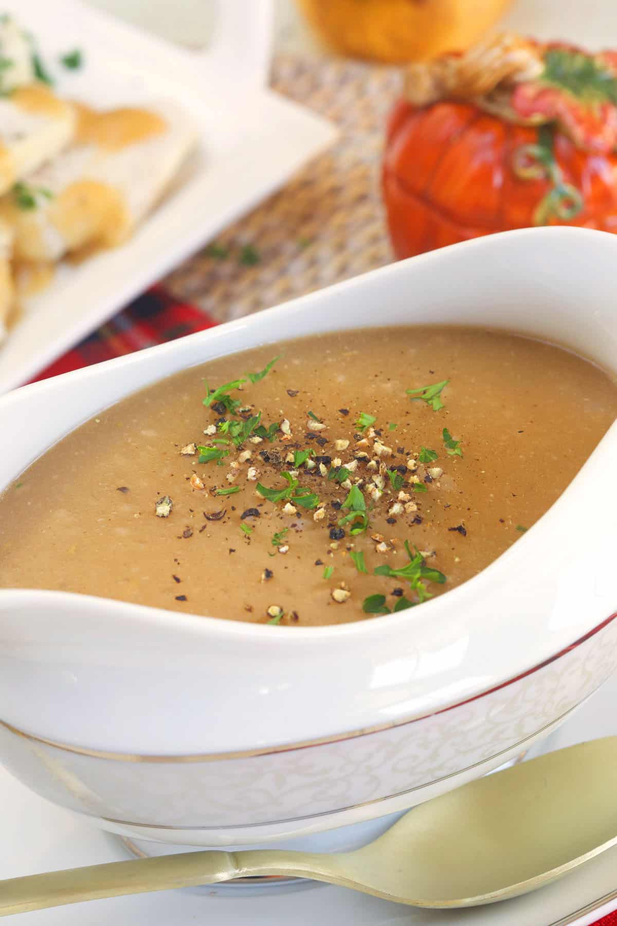 A white gravy boat is filled with brown turkey gravy. 
