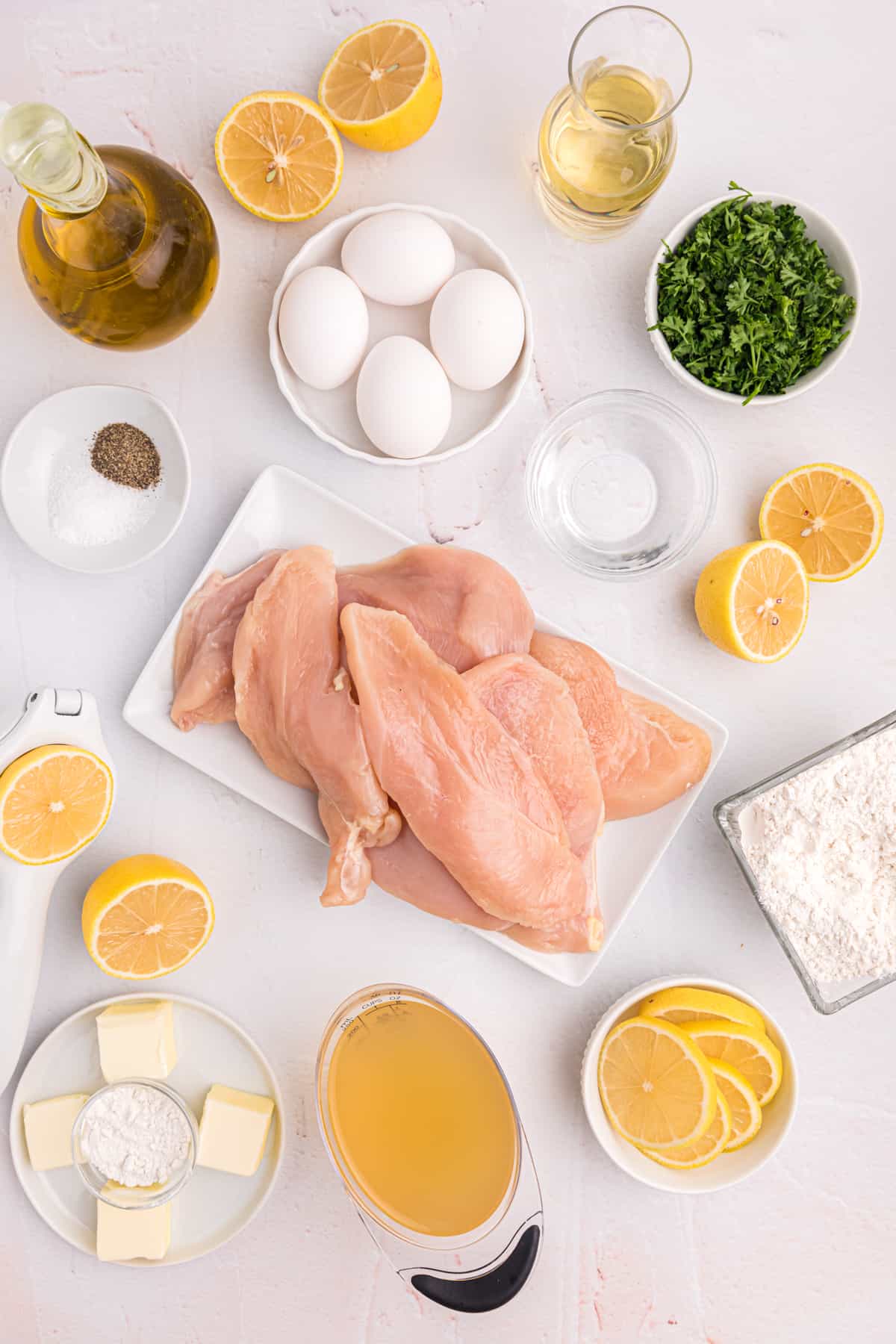 The ingredients for chicken francese are placed on a white countertop. 