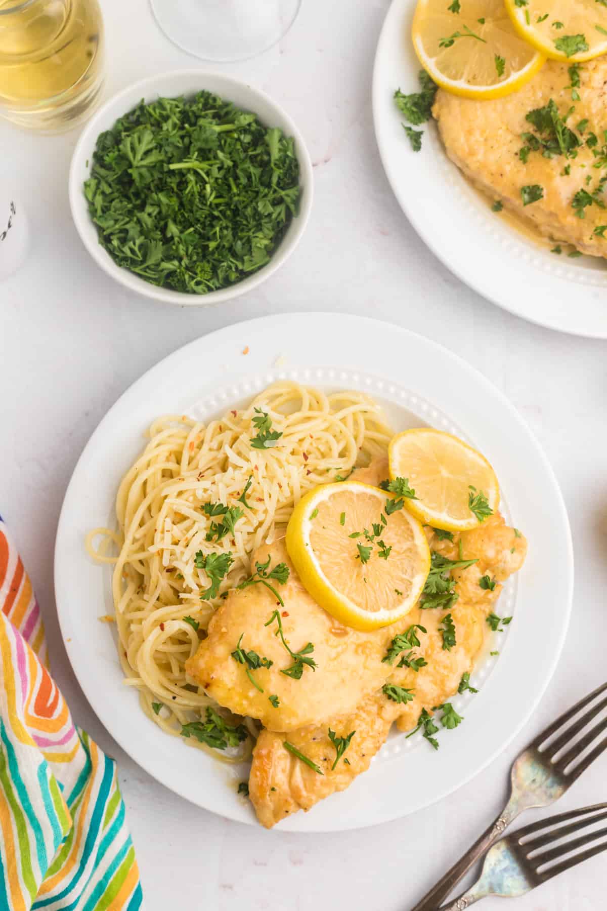 Chicken francese is served with pasta on a white plate.