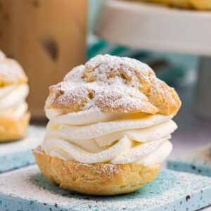A cream puff is plated and dusted with powdered sugar.