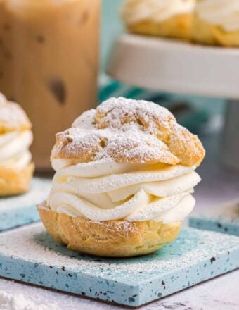 A cream puff is plated and dusted with powdered sugar.