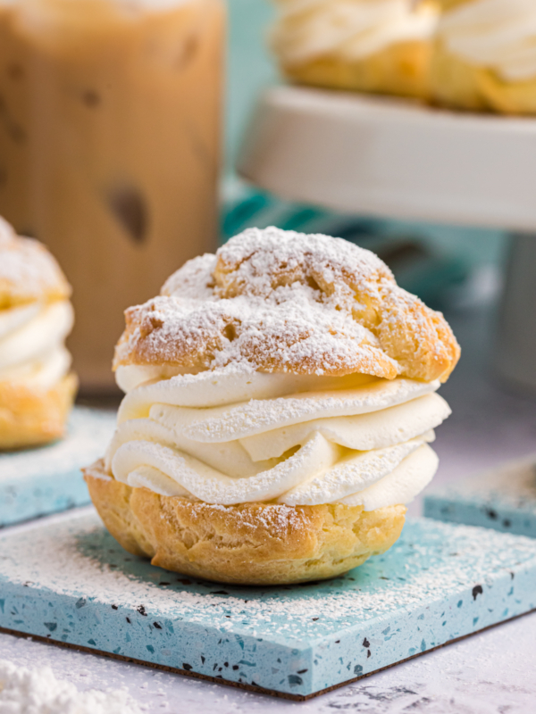 A cream puff is plated and dusted with powdered sugar.