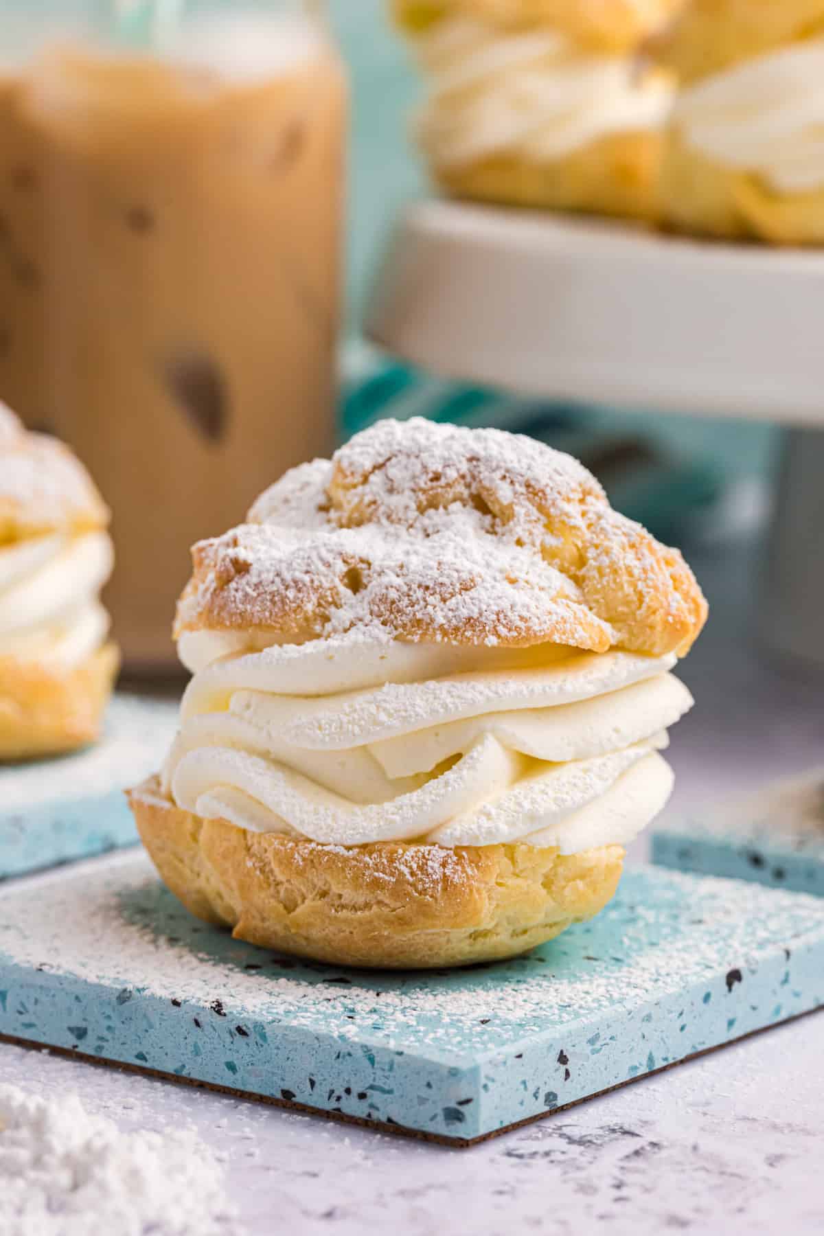 A cream puff is plated and dusted with powdered sugar. 