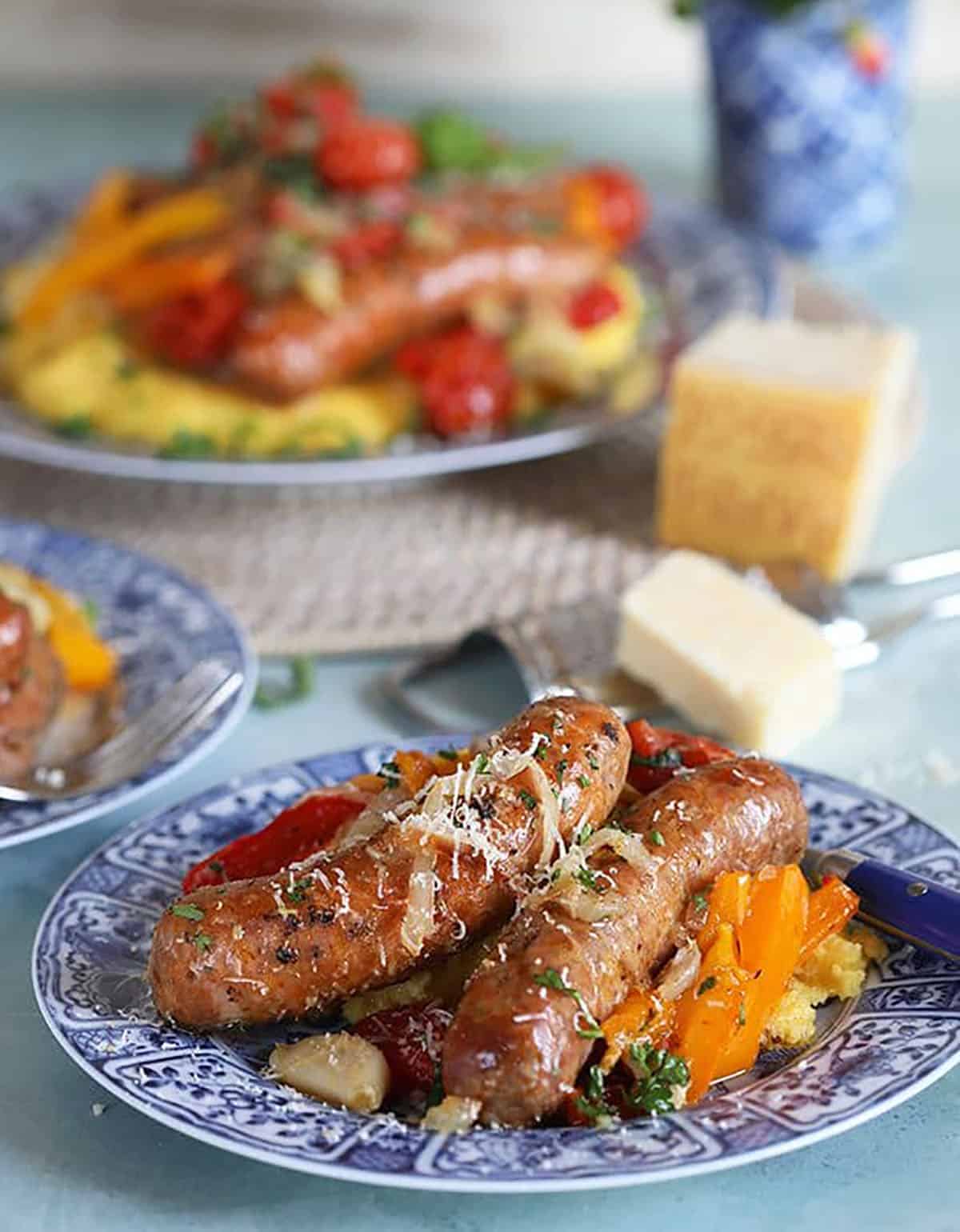 Italian sausage and peppers on parmesan polenta on a blue and white plate.