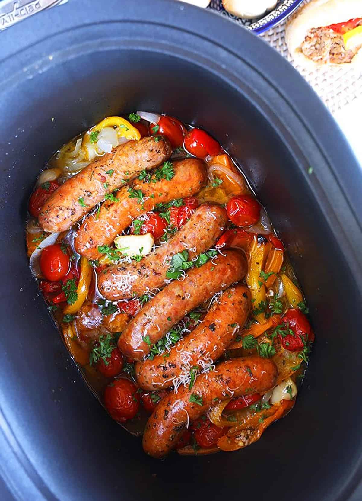 Italian sausage and peppers in a black cast iron crock pot.
