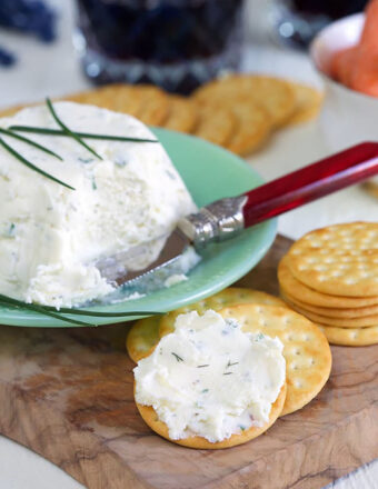 White creamy Boursin cheese is spread on a cracker.