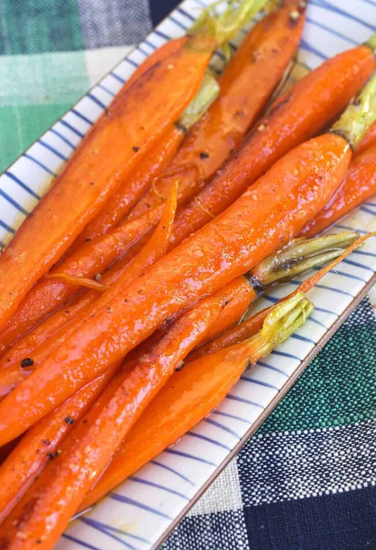 A striped plate is topped with cooked carrots.