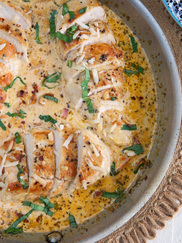 Sliced chicken is placed in a skillet filled with a creamy sauce.