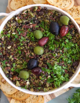 A white bowl is filled with olive tapenade.