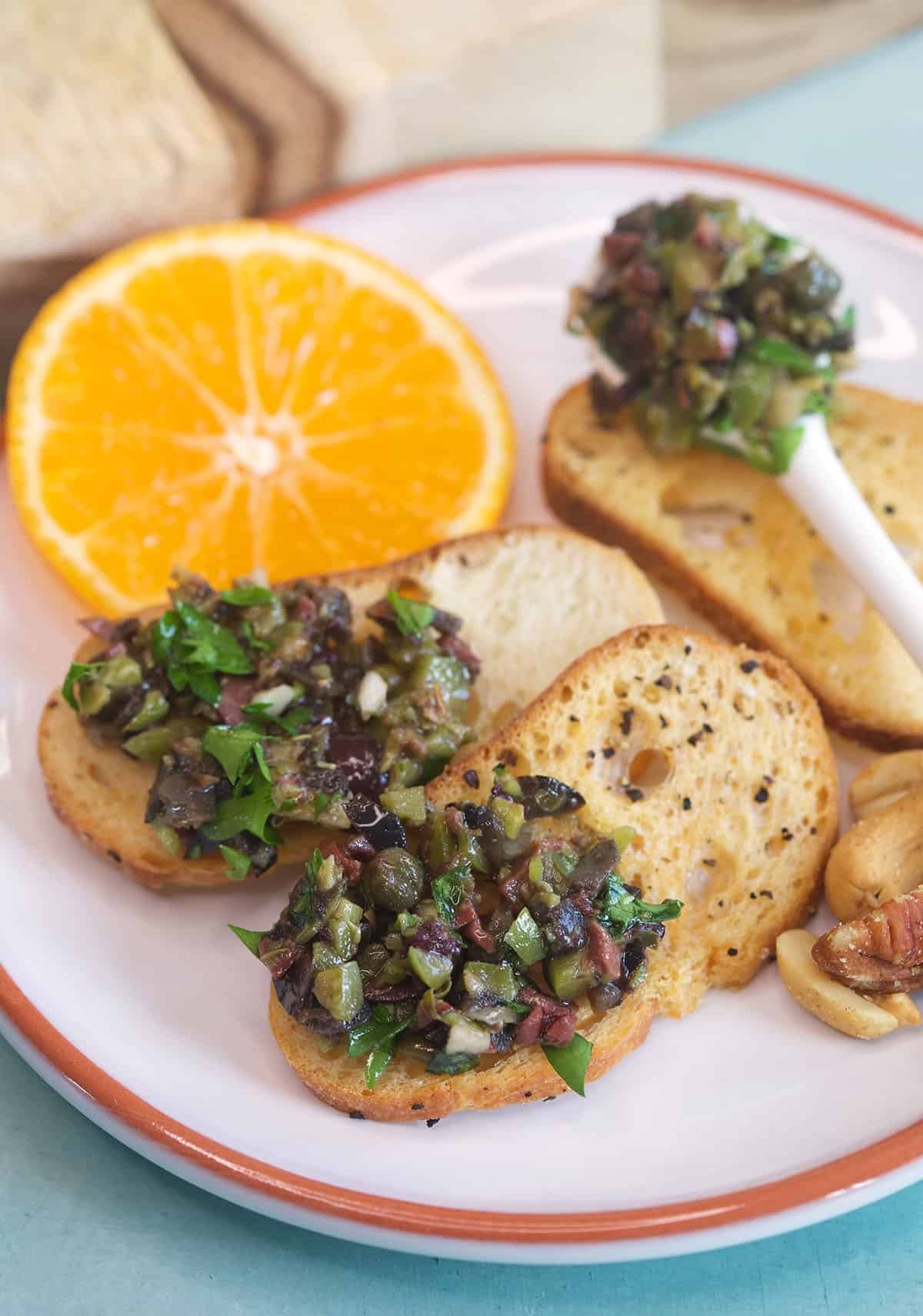 Several pieces of crunchy crostini are topped with olive tapenade. 