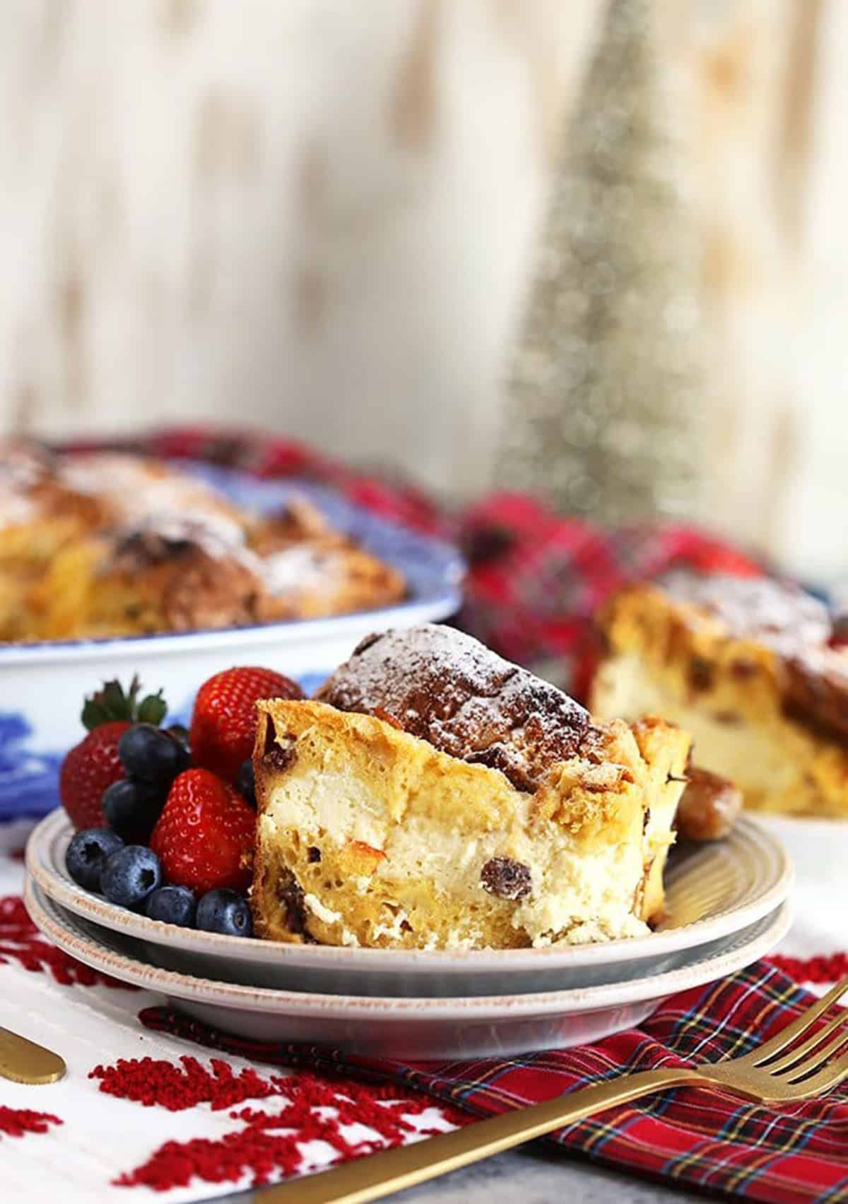 Cheesecake Stuffed Panettone French Toast Casserole on a white plate with plaid napkin.