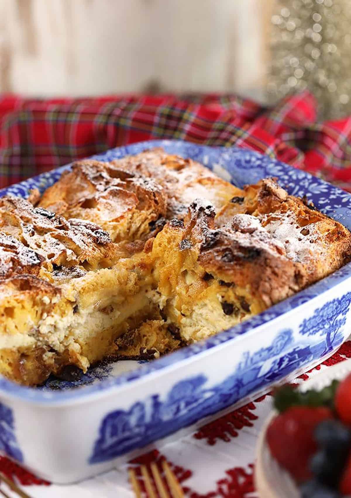 Panettone French Toast Casserole in a blue and white casserole dish with a plaid napkin in the background.