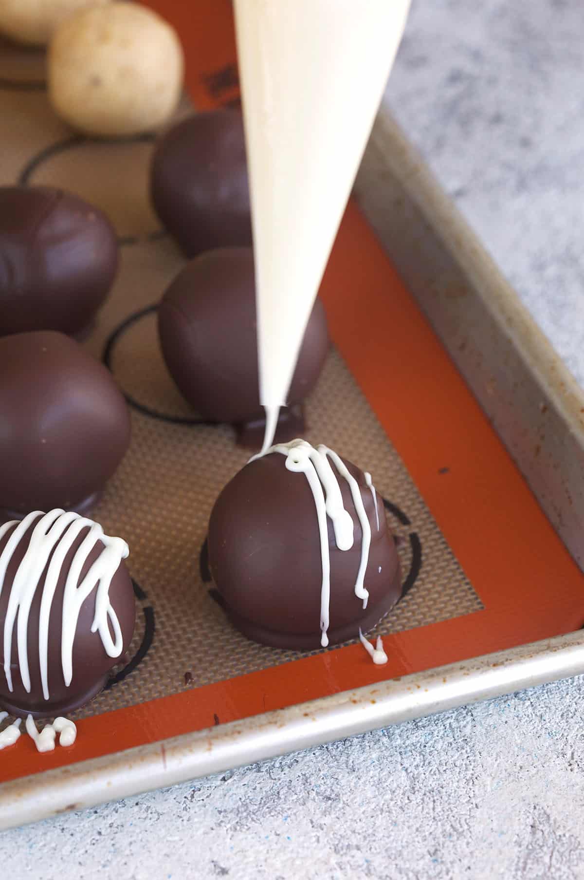 White chocolate is being drizzled over a peanut butter ball.