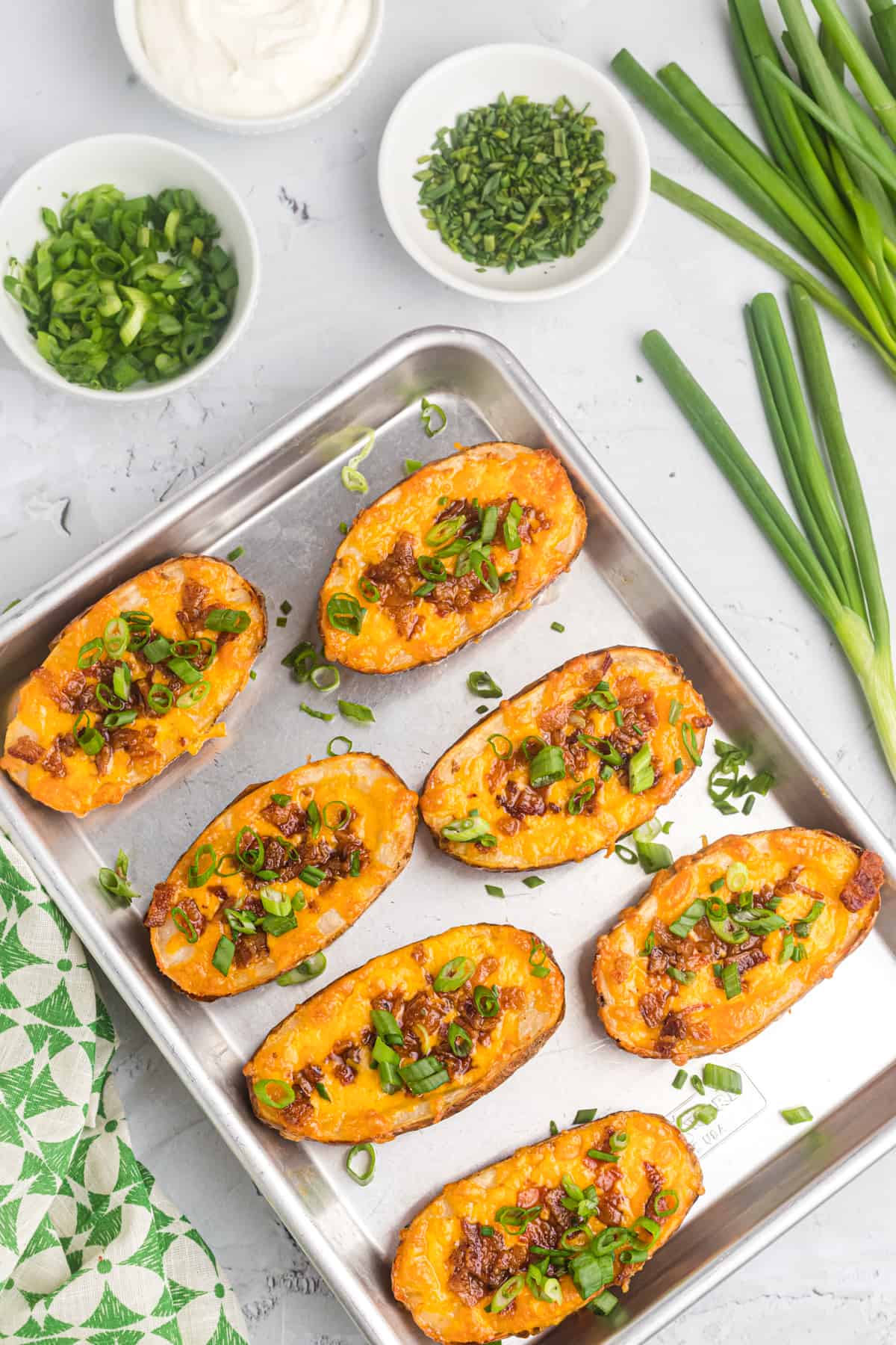 Baked loaded potato skins are placed on a baking sheet.