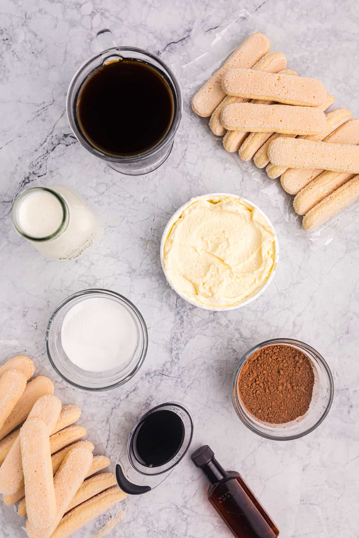 The ingredients for tiramisu are spread out on a marble countertop. 