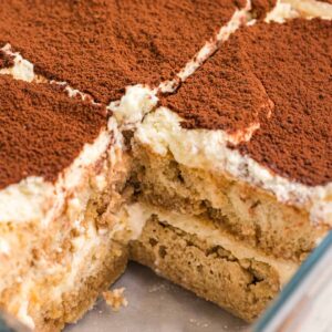 Tiramisu has been sliced into several pieces in a baking dish.