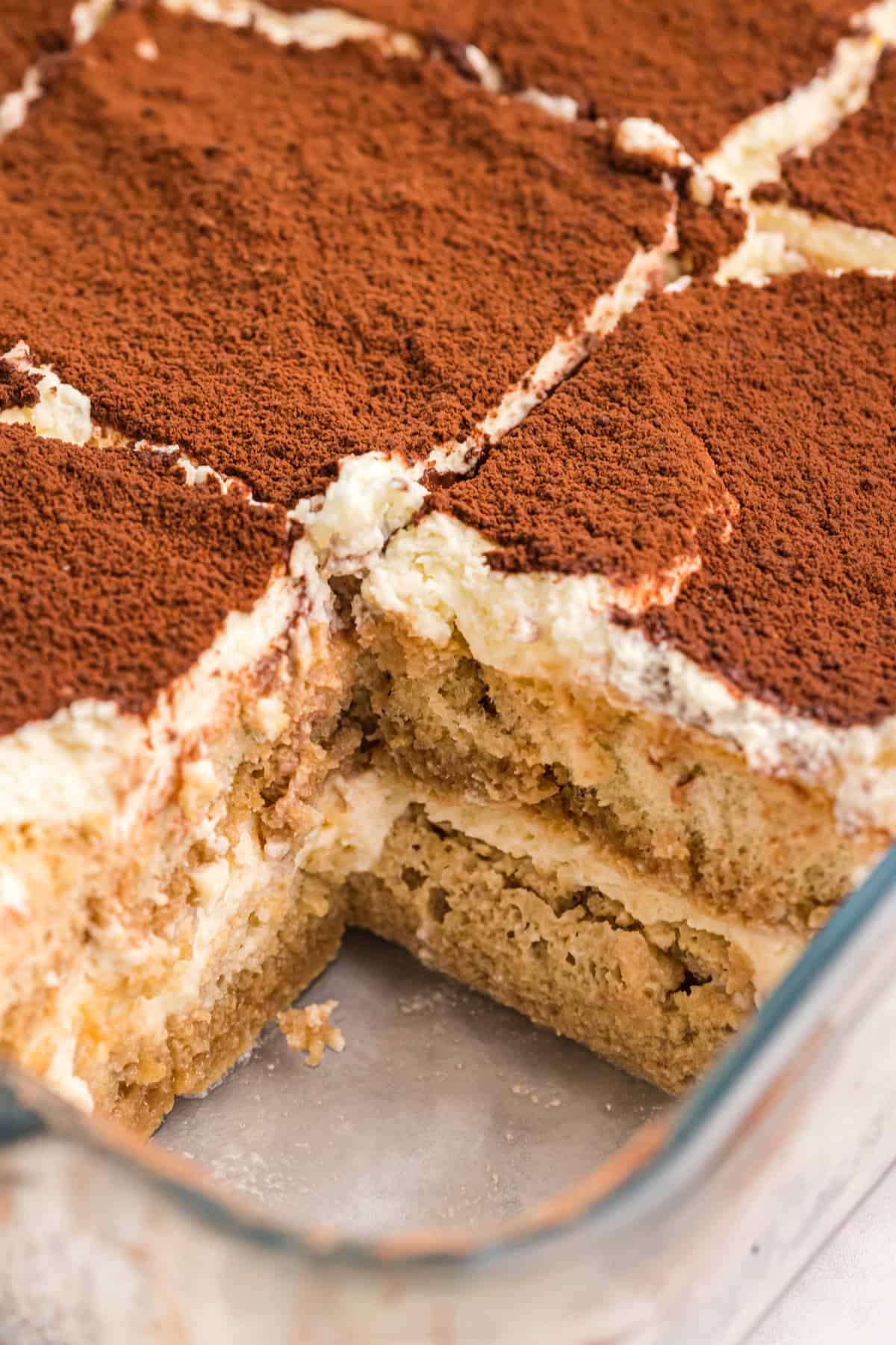 Tiramisu has been sliced into several pieces in a baking dish.