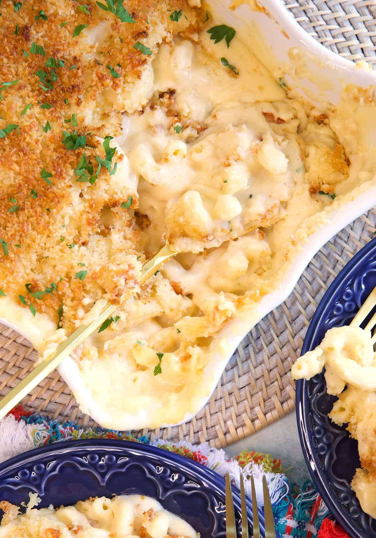 Five cheese baked Mac and cheese in a white casserole dish with a gold serving spoon in it.