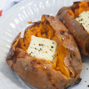 A square of butter is placed in the inside of a cooked sweet potato.