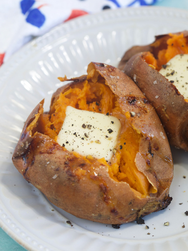 A square of butter is placed in the inside of a cooked sweet potato.