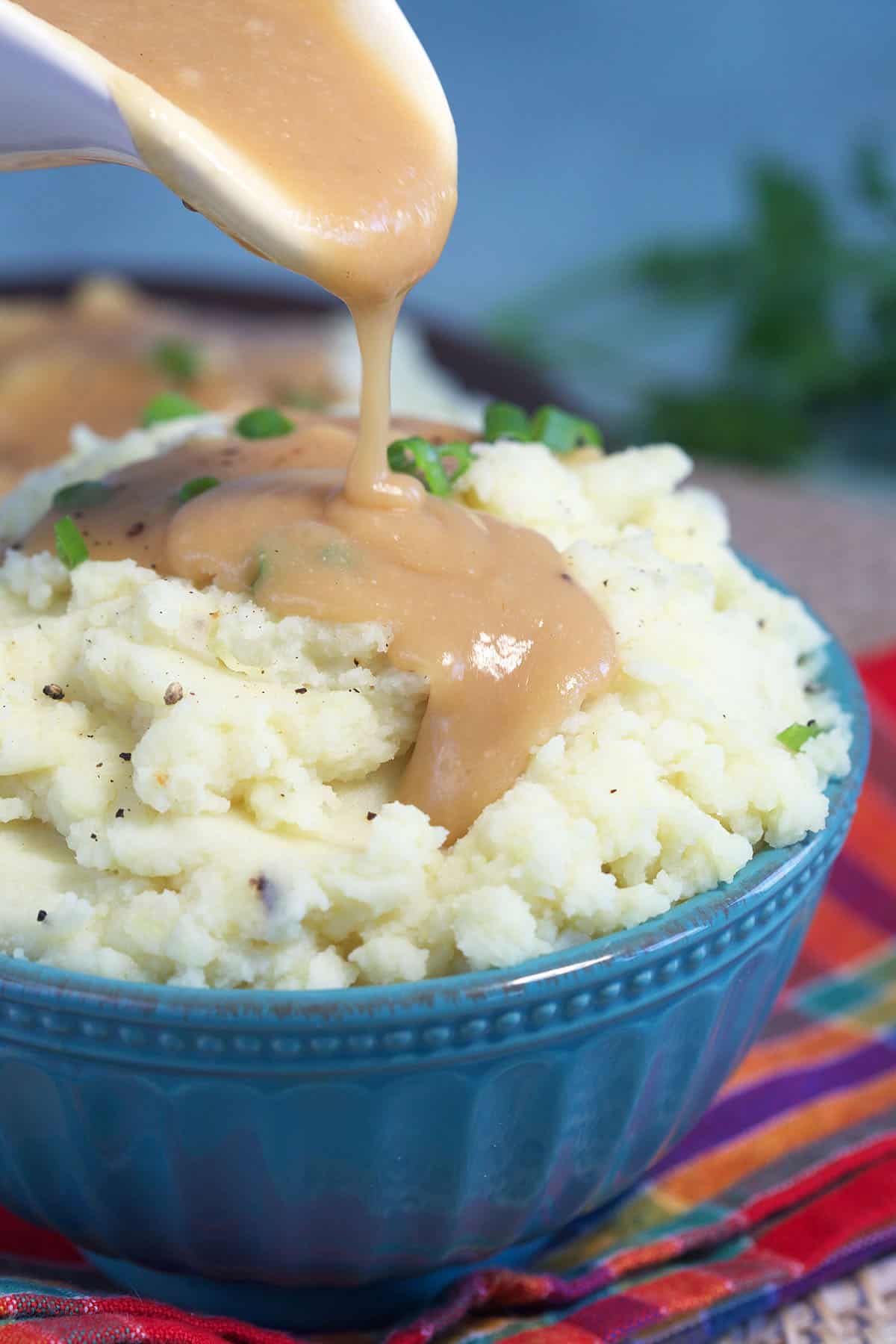 Gravy is being poured on top of mashed potatoes.