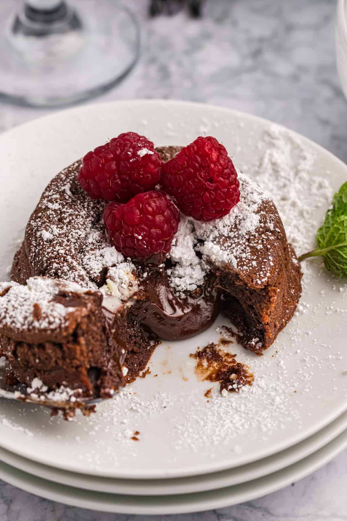 Fresh raspberries and powdered sugar are placed on top of a chocolate lava cake.