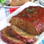 Meatloaf with two slices on a white platter.