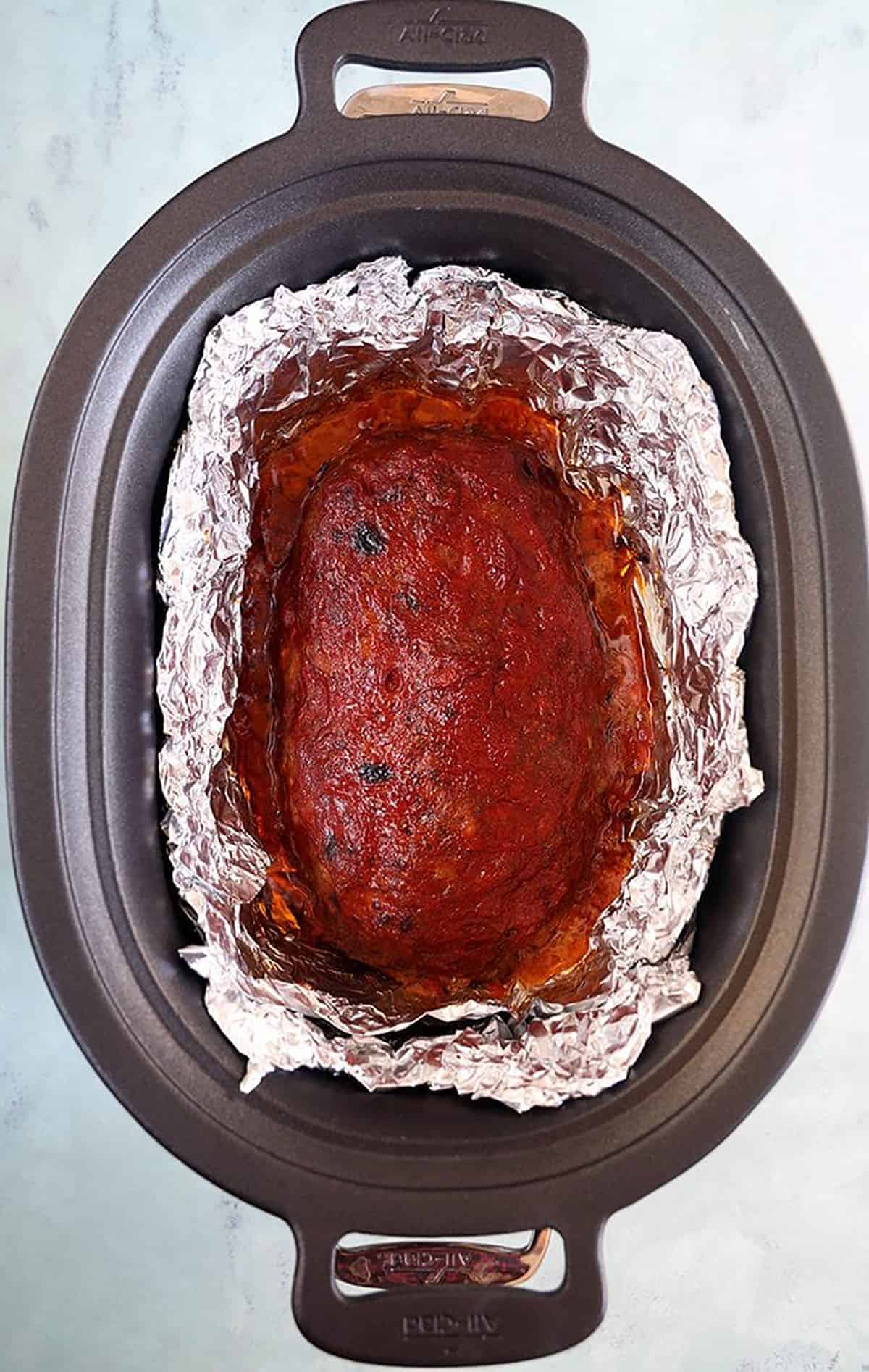 Crockpot with a meatloaf in foil inside the crockpot.