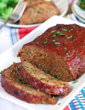 Meatloaf with two slices on a white platter.