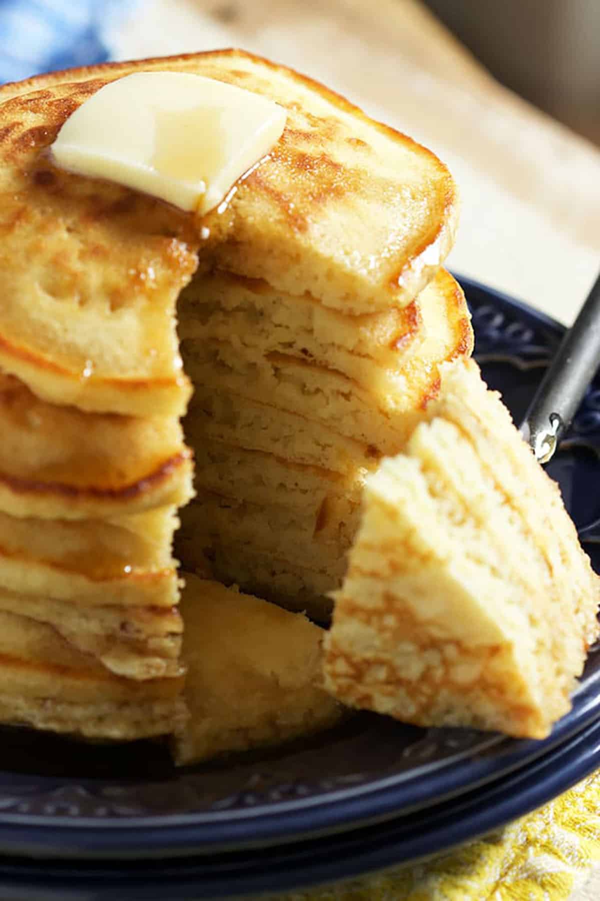 Stack of pancakes with a wedges cut out and on a fork.