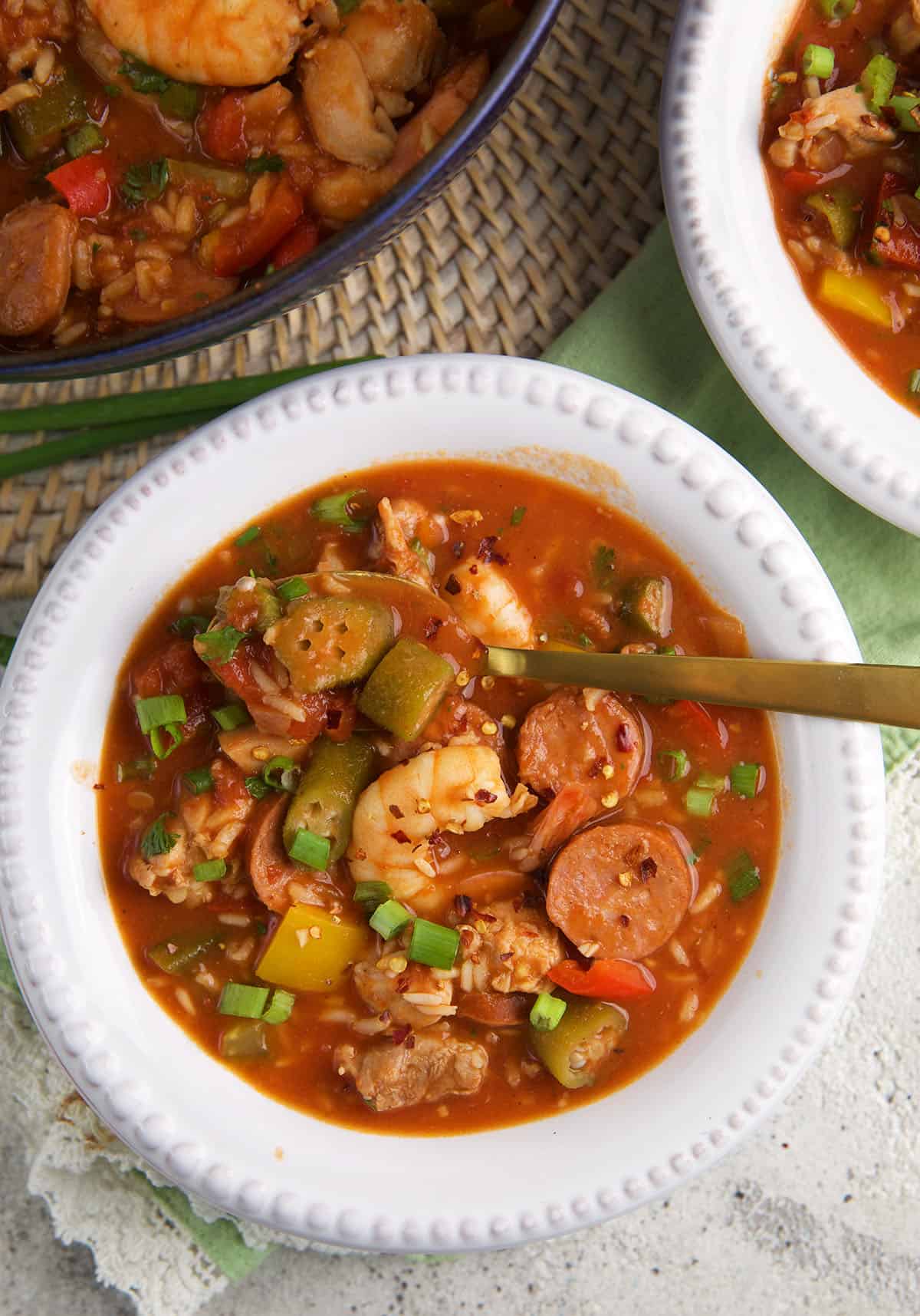 A white bowl is filled with jambalaya and is served with a spoon. 