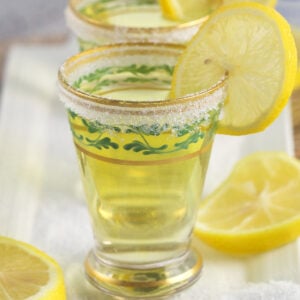 Several shot glasses are garnished with lemon slices and a sugar rim.