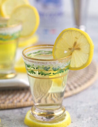 A shot glass is placed on top of a lemon slice.