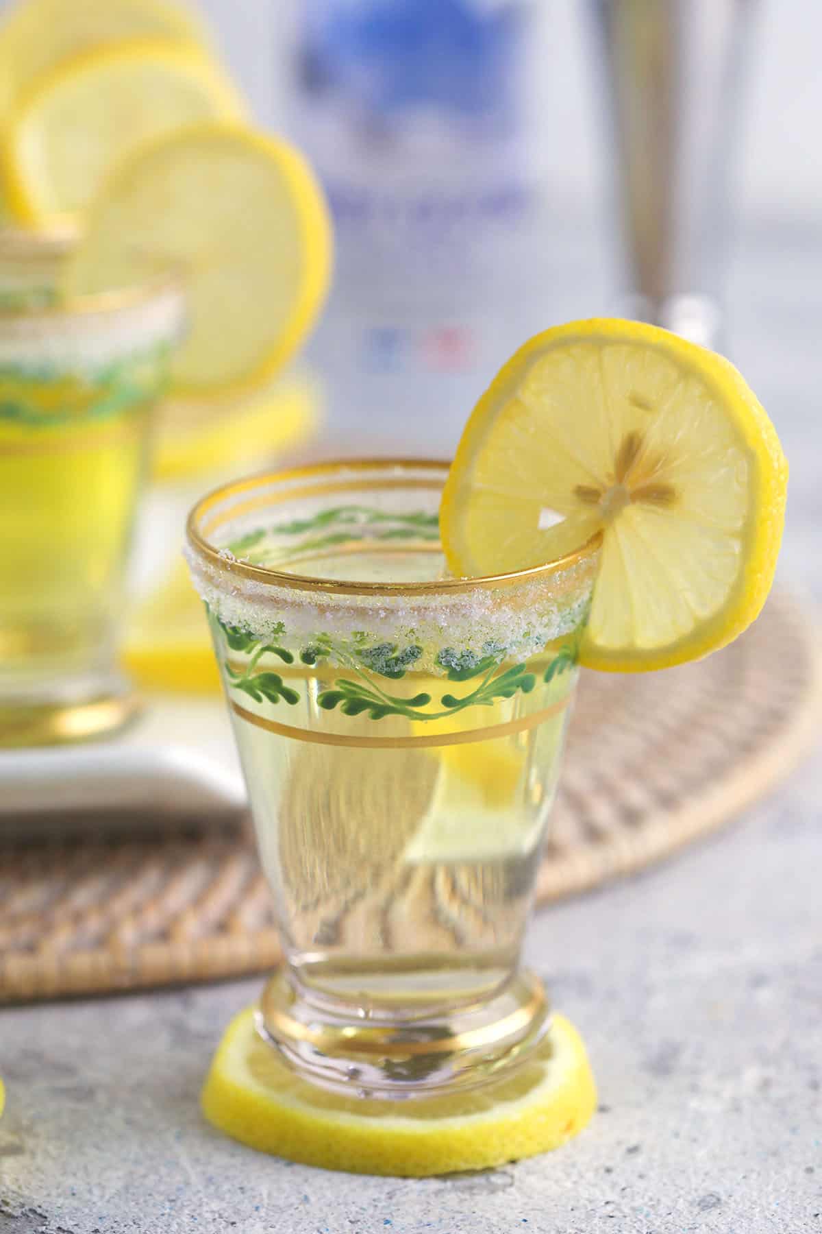 A shot glass is placed on top of a lemon slice.