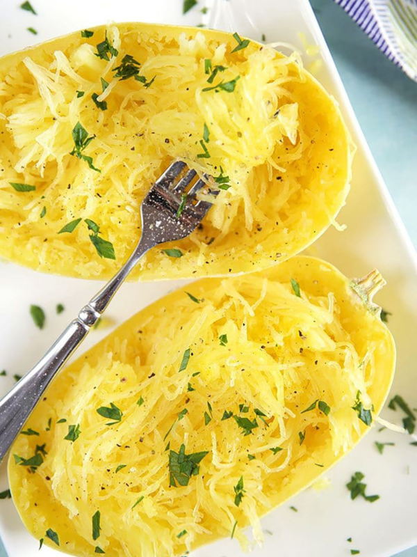 Cooked spaghetti squash with a fork on a white plate.