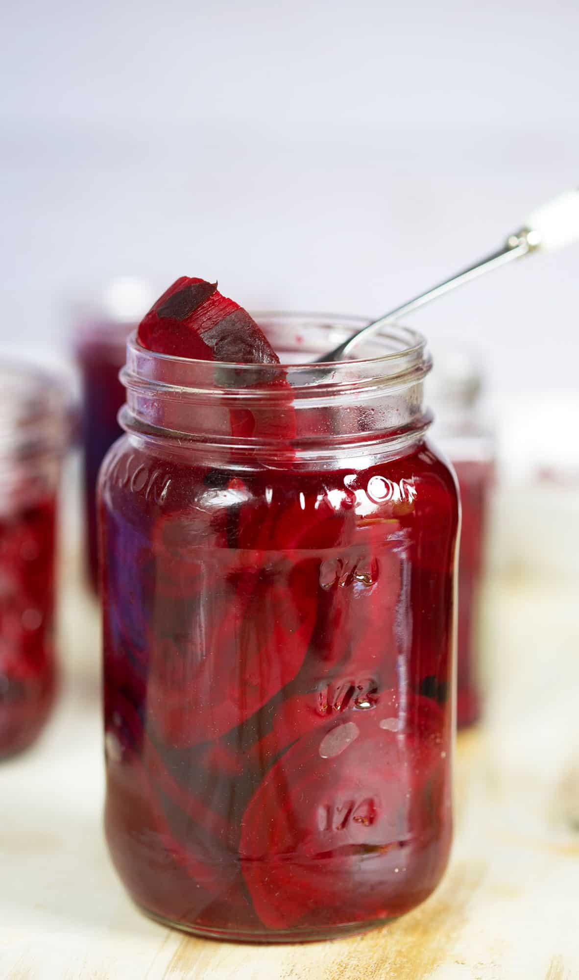 A jar of pickled beets is placed on a countertop. 