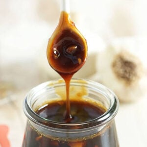 Teriyaki Sauce being drizzled into a jar with a white spoon.