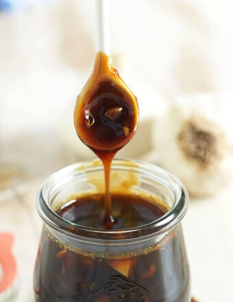 Teriyaki Sauce being drizzled into a jar with a white spoon.