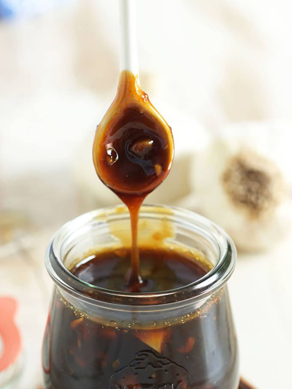 Teriyaki Sauce being drizzled into a jar with a white spoon.