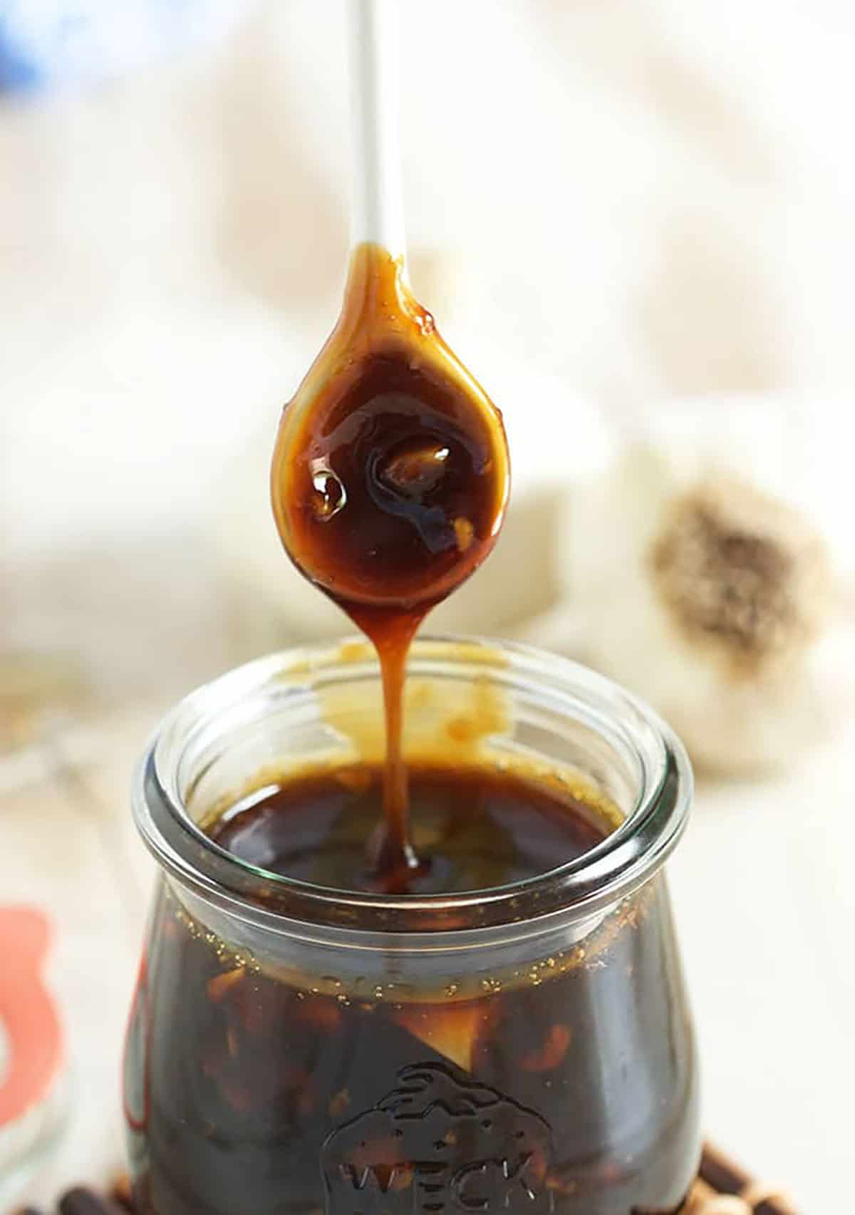 Teriyaki Sauce being drizzled into a jar with a white spoon.