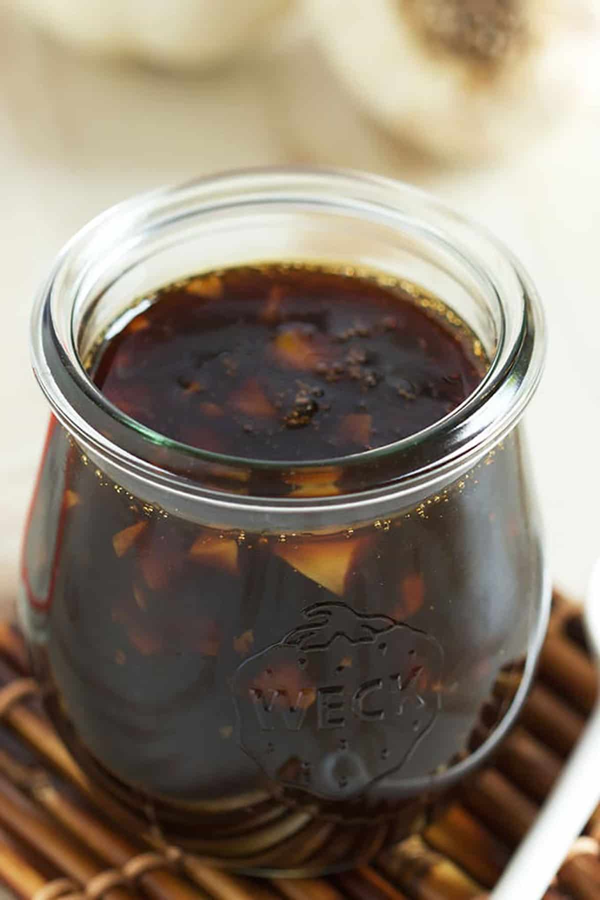 Teriyaki Sauce in a small jar on a bamboo coaster.