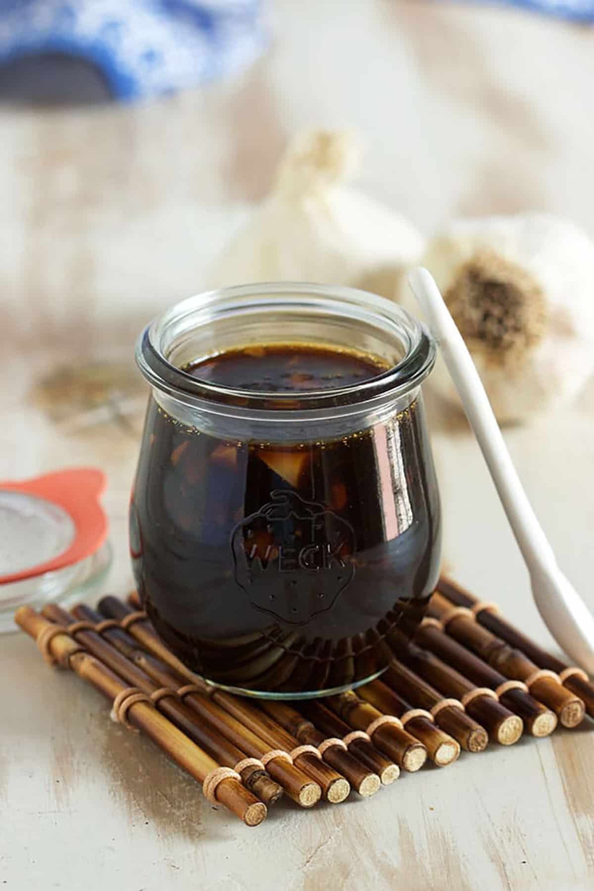 tulip jar of teriyaki sauce on a bamboo coaster