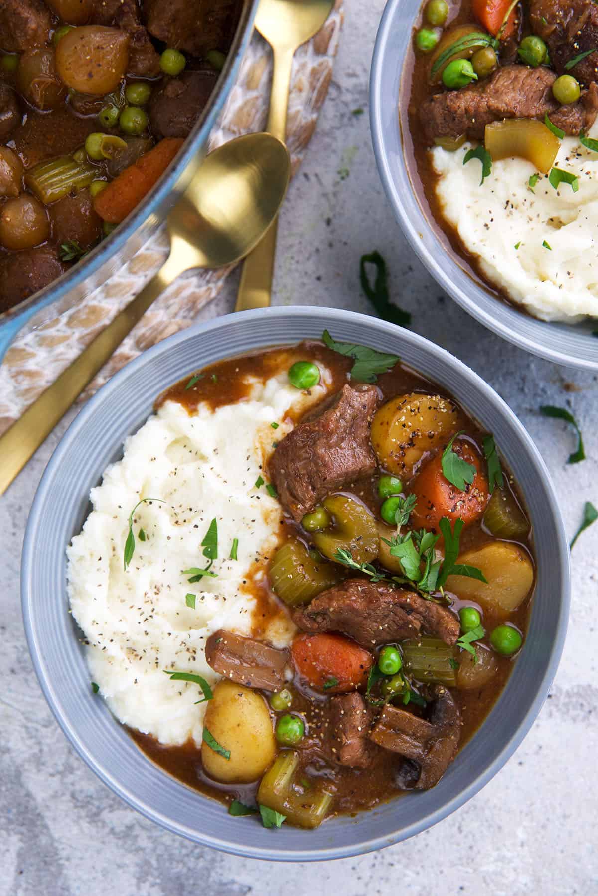 Beef stew is placed in a blue bowl with mashed potatoes. 