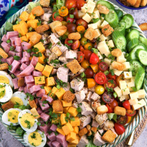 A large bowl filled with chefs salad is placed on a tabletop.